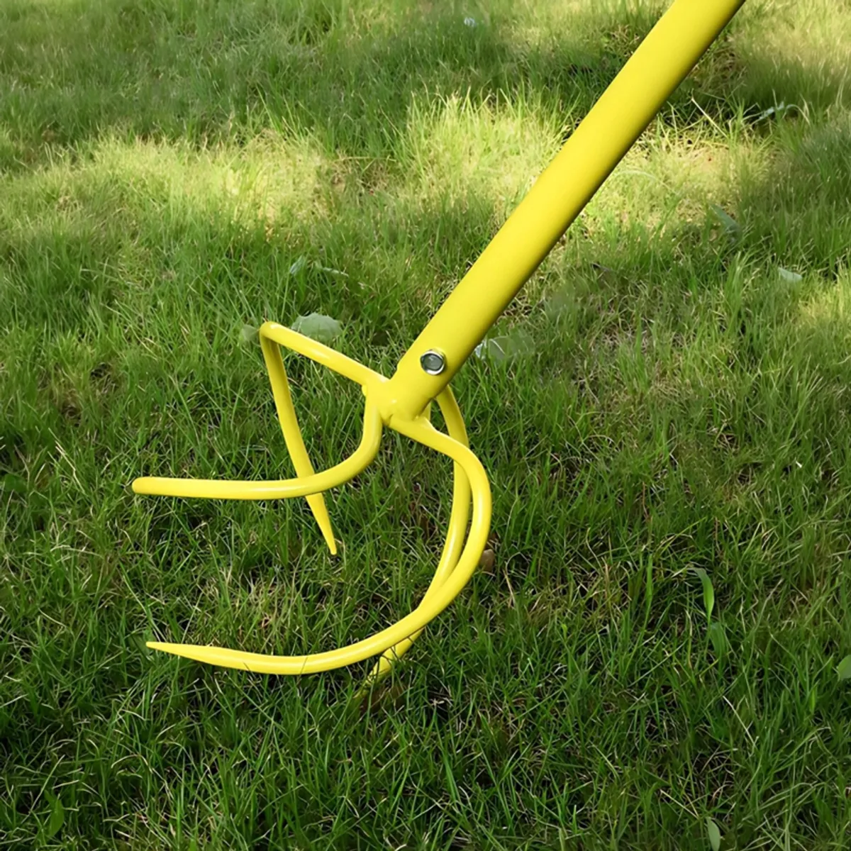 Close-up of the yellow curved soil-auger tines on grass