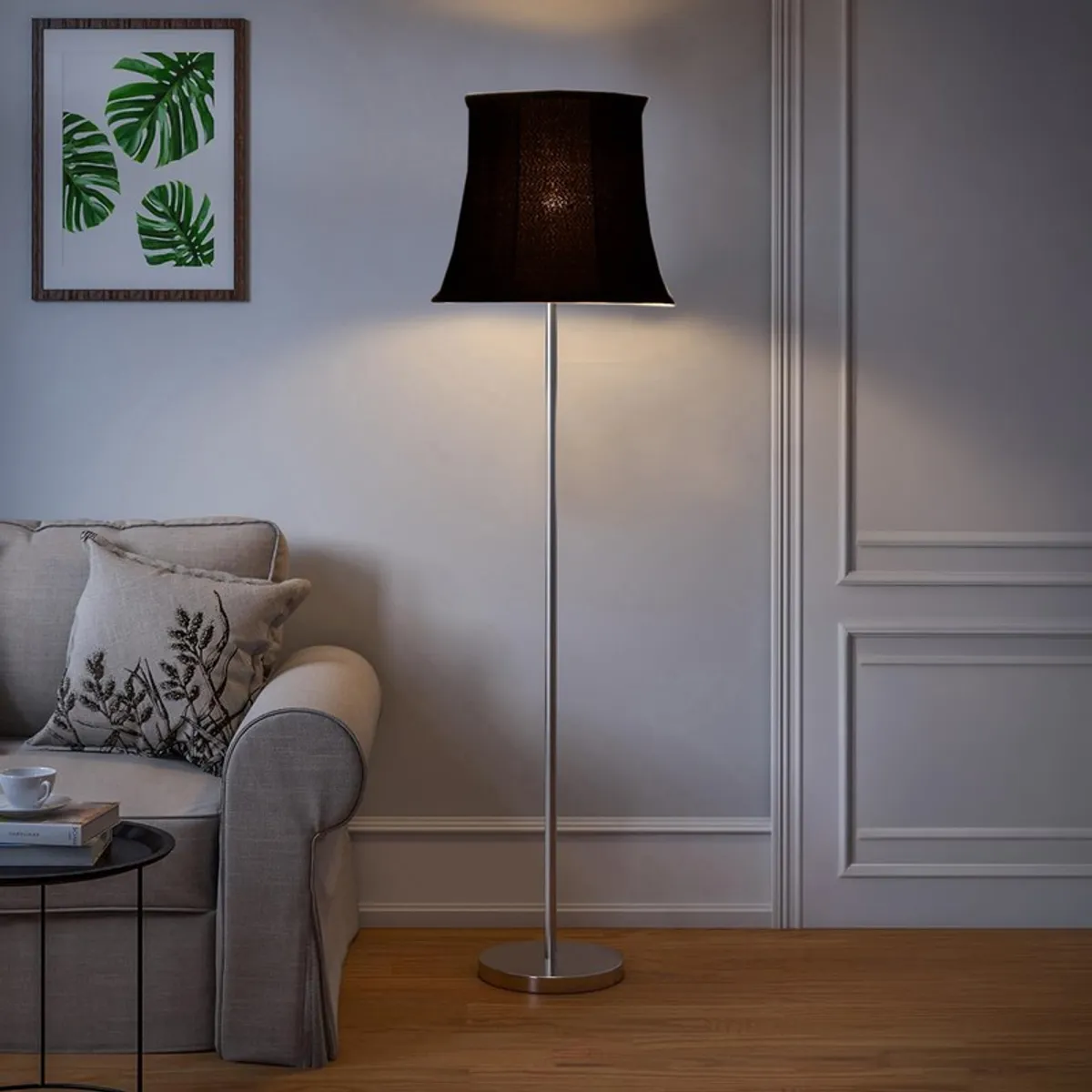 Lit black floor lamp with round base in a classic living room corner