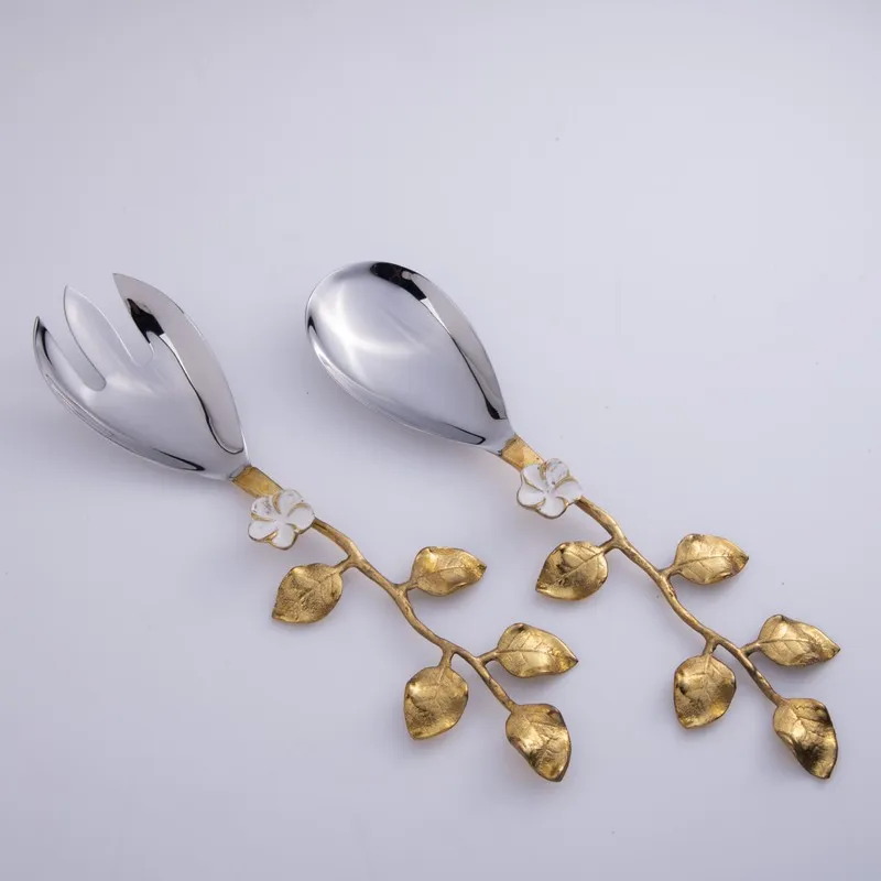 Close view of silver salad spoon and fork with gold leaf handles