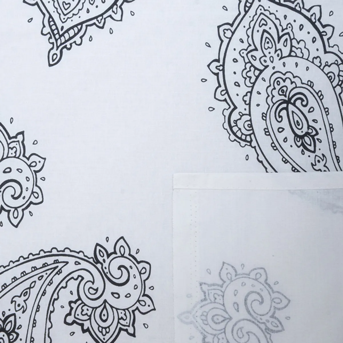 Close-up of black paisley motifs on white bedsheet fabric