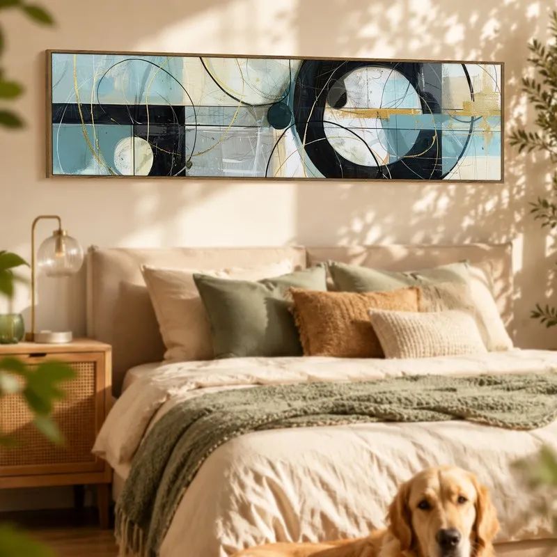Framed abstract canvas in blue, black and gold above a bed in a sunlit room