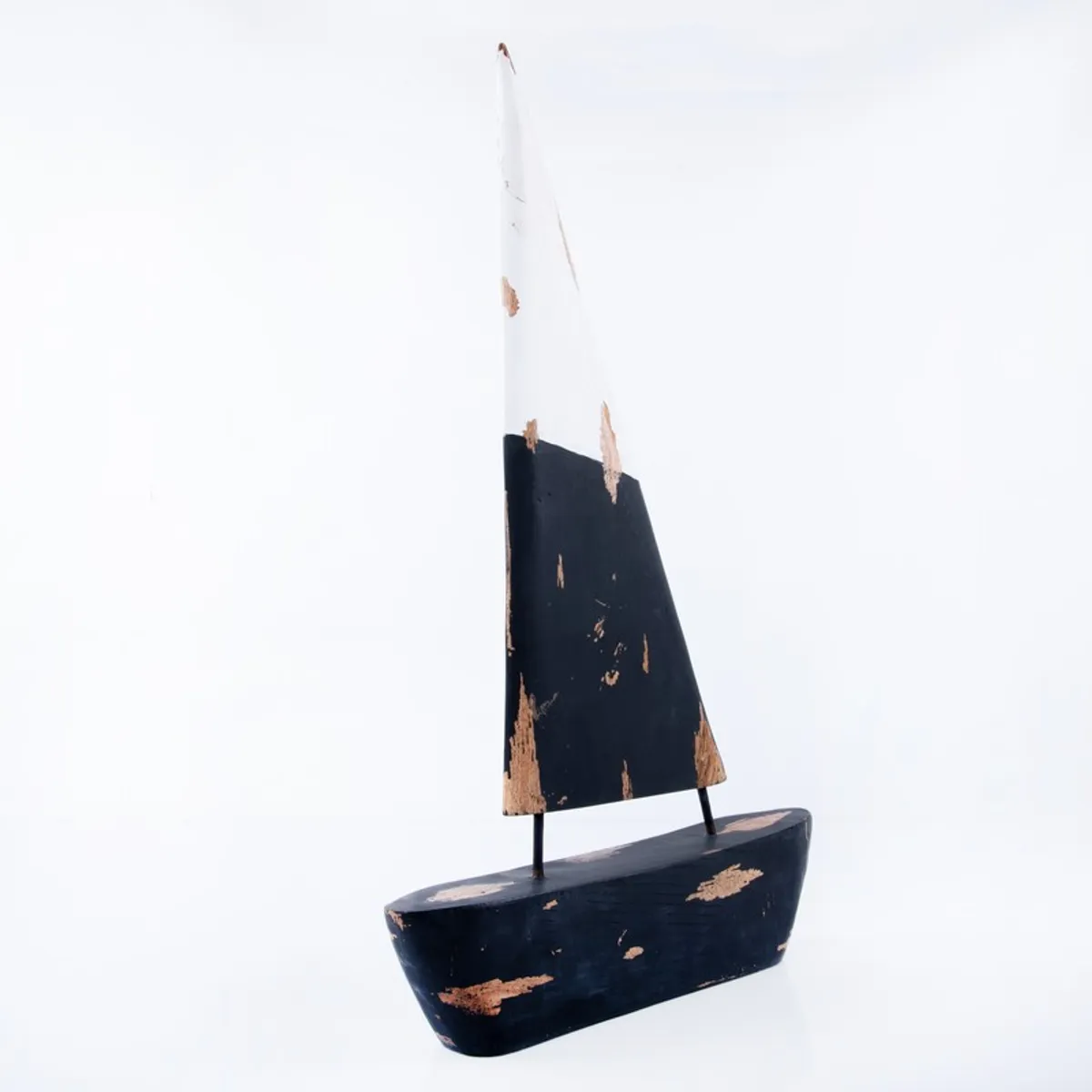 Side view of a black and white sailboat showpiece with rustic surface details