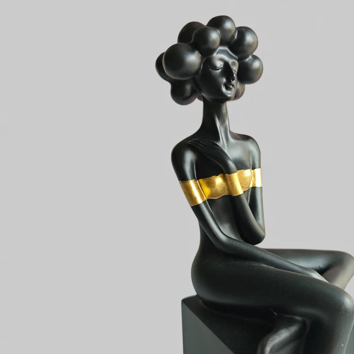 Close-up view of the glossy black figurine with a gold band and bubble-style hair