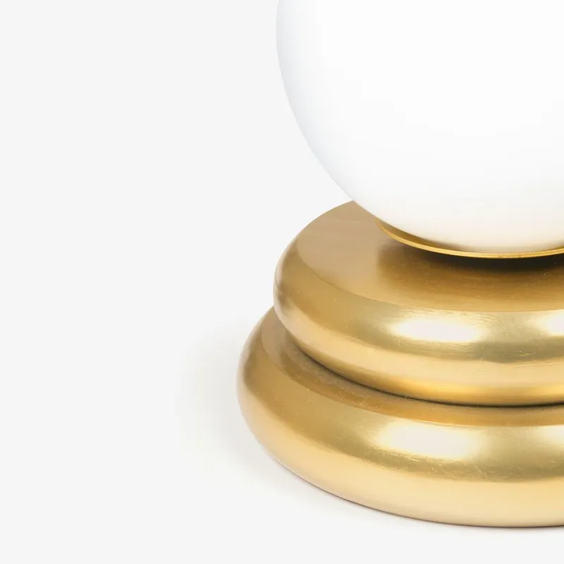Side close-up of the white globe shade and gold base