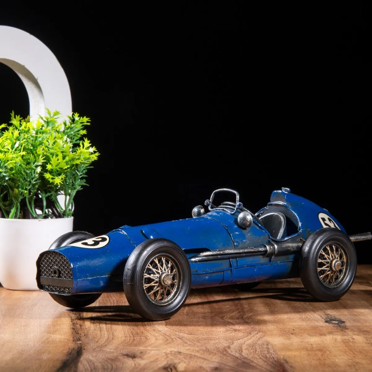 Blue iron racing car showpiece with detailed wheels on a wooden surface