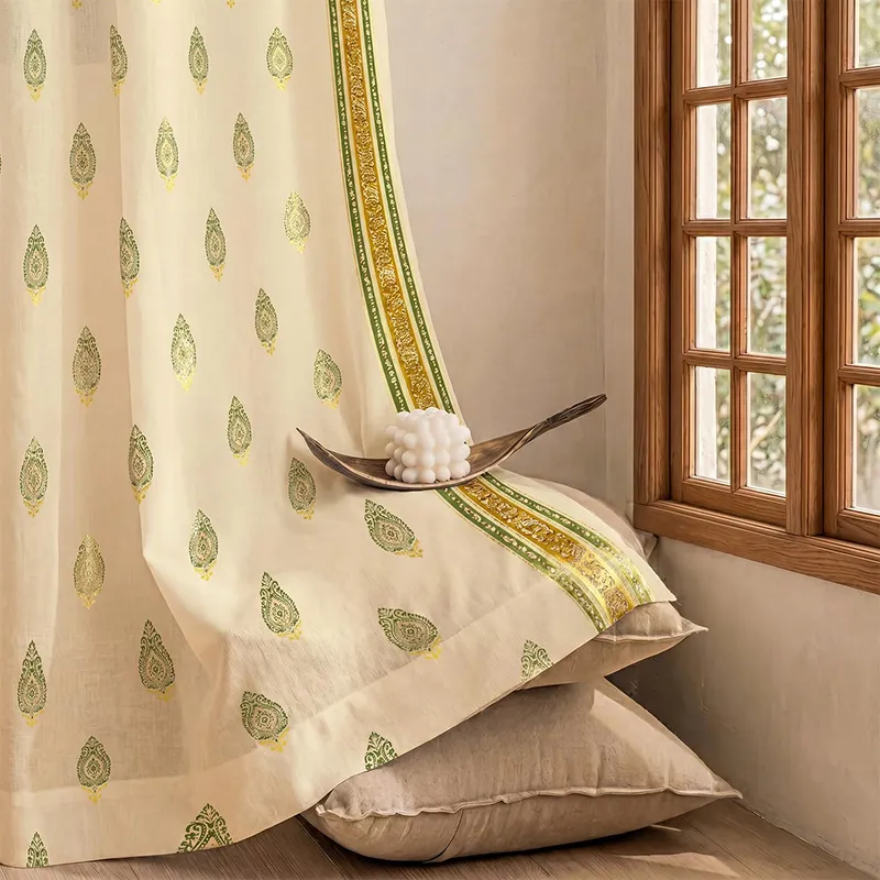 Off-white curtain with sage green buta motifs and gold border near a wooden window