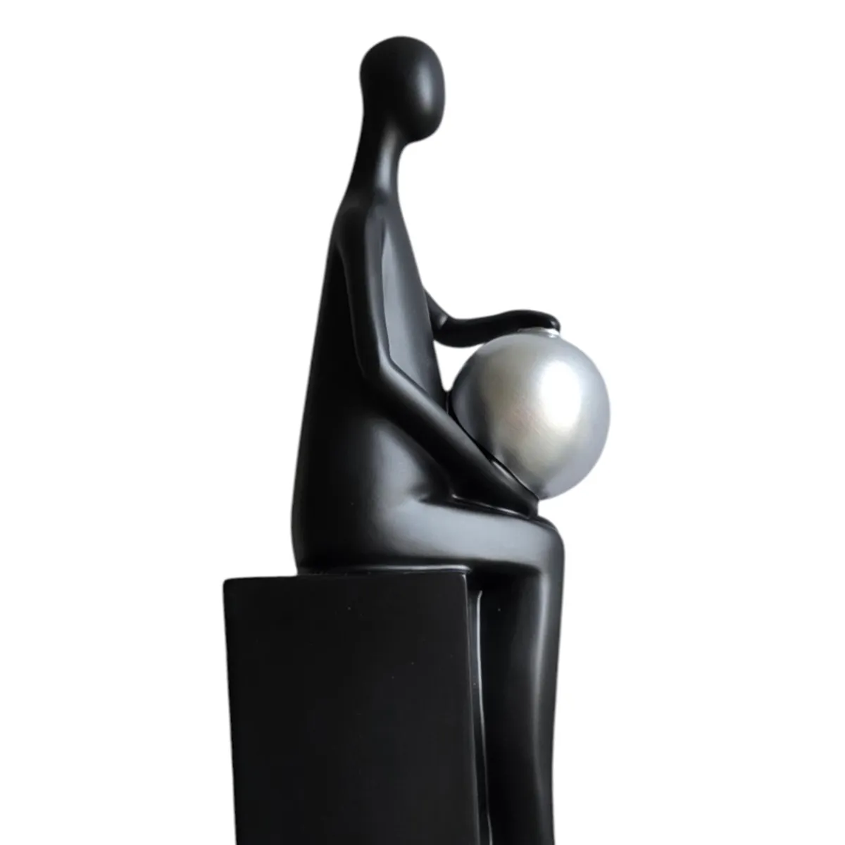 Close side view of a black figurine holding a silver sphere