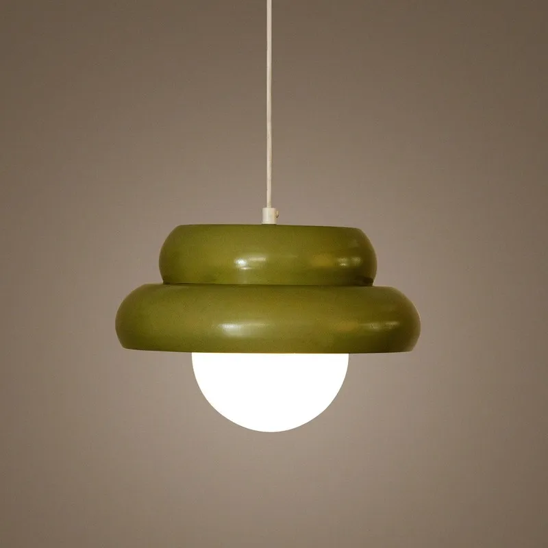 Lit pistachio green ceiling lamp with white globe shade against a beige wall
