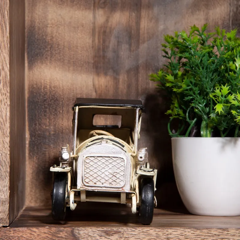 Front view of a vintage car iron showpiece beside a planter