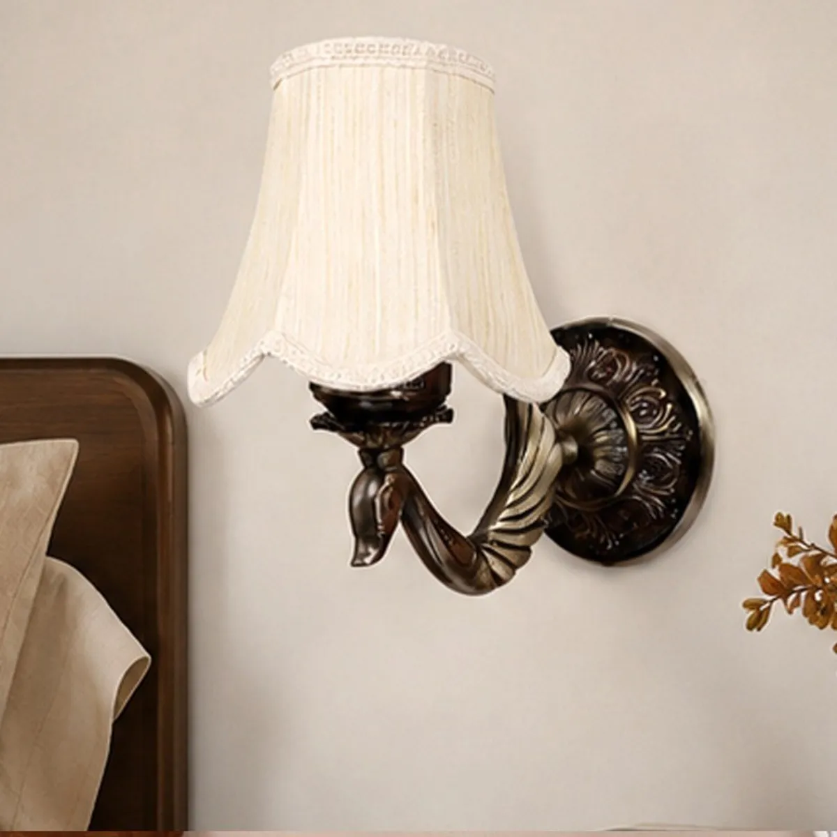 Close view of a white cotton-shade wall lamp with ornate dark metal wall plate