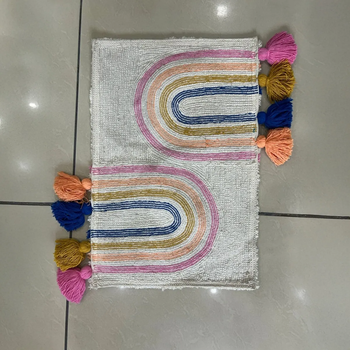 Close overhead view of the bath mat showing its colourful arch pattern and tassels