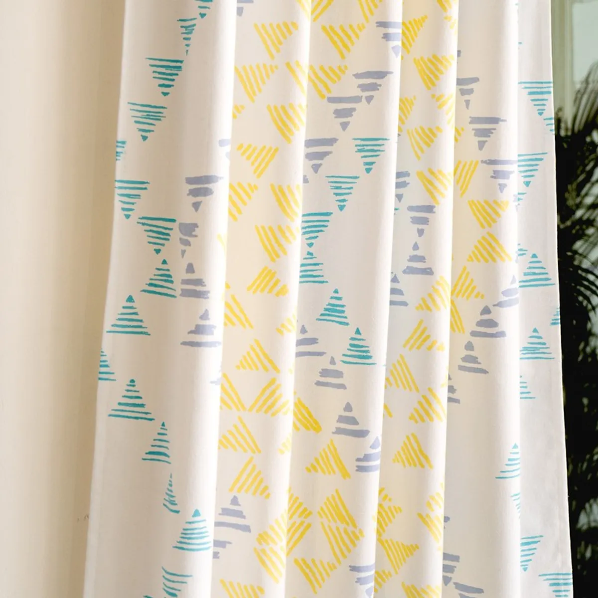 Draped white curtain showing yellow, blue and turquoise geometric motifs