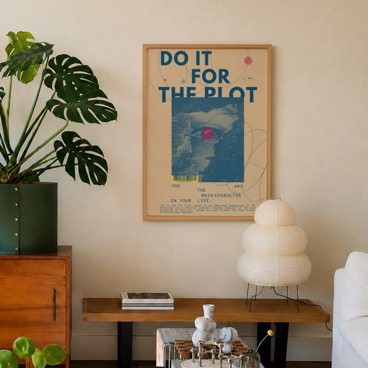 Framed blue and beige wall art displayed beside a leafy plant