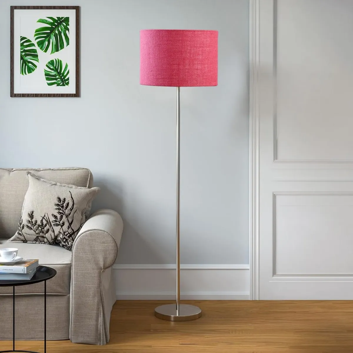 Pink floor lamp with drum shade and round steel base in a bright room