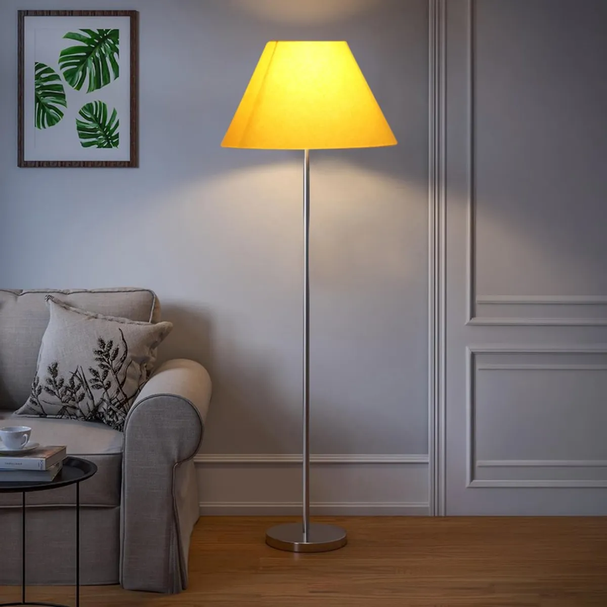 Yellow floor lamp glowing beside a grey sofa in a neutral room