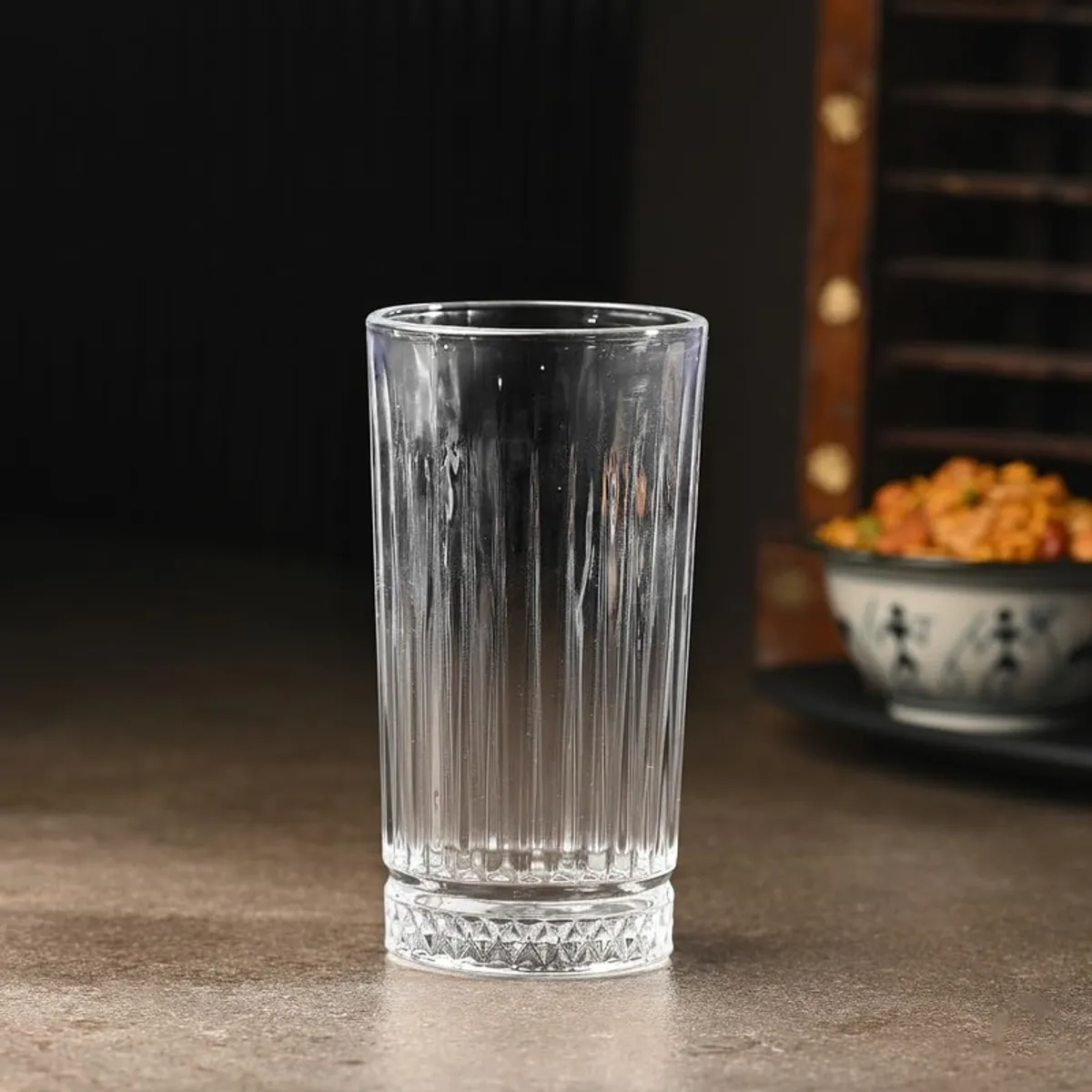 Single clear textured drinking glass with a patterned base