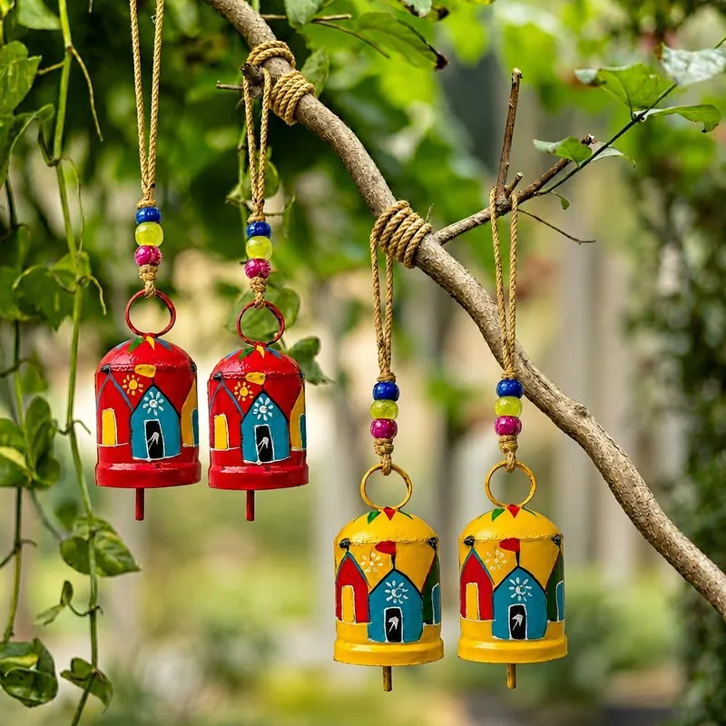 Four multicolour hanging bells suspended from a tree branch outdoors
