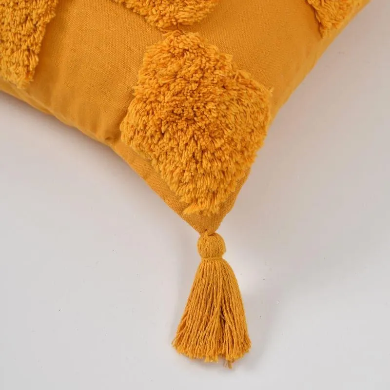 Close-up of the yellow tufted cushion cover corner with tassel detail