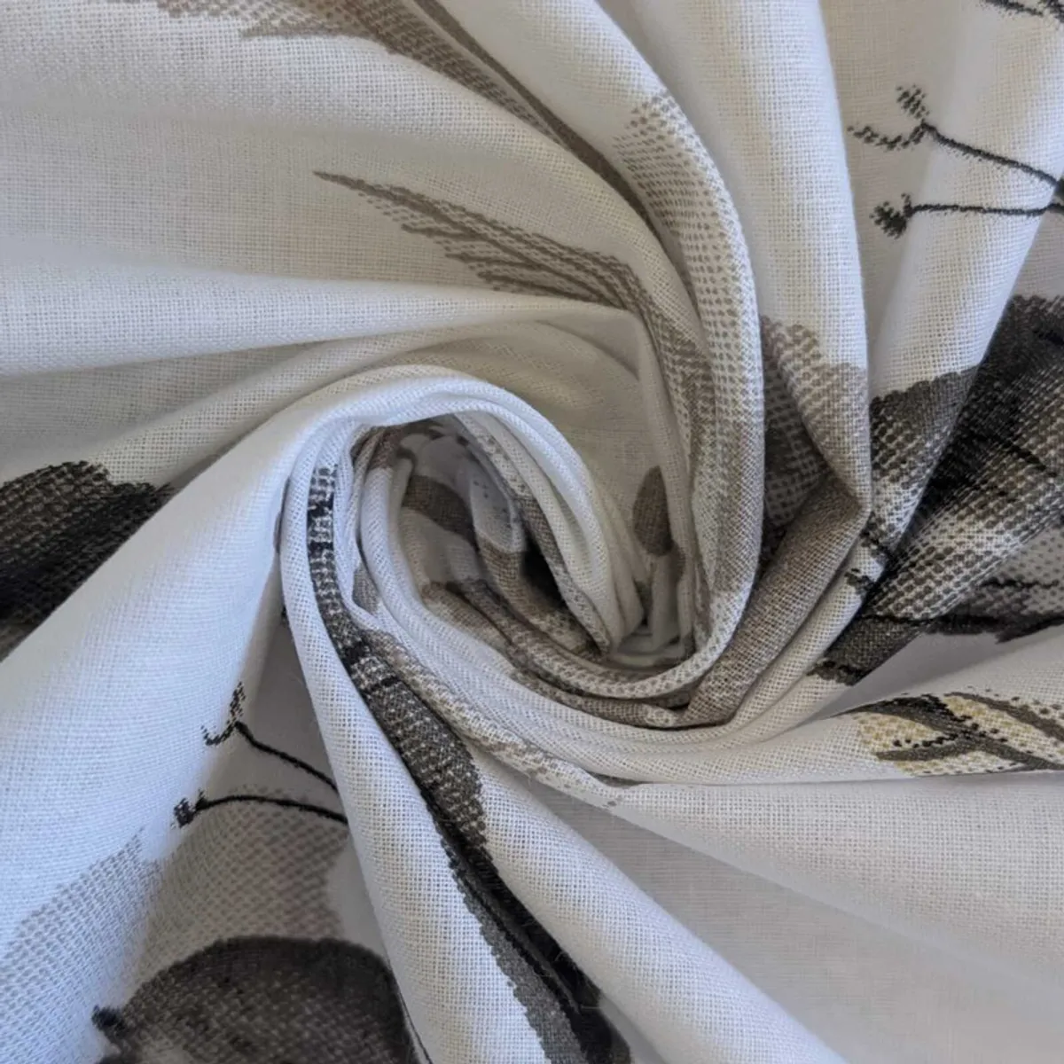 Close-up of white cotton fabric gathered to show its floral print texture