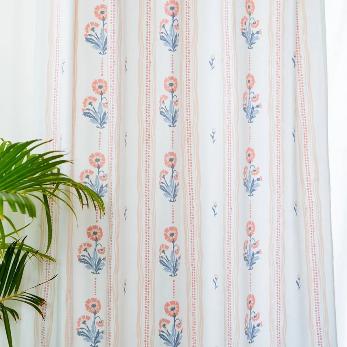 Floral curtain panels shown beside a leafy plant in a bright room