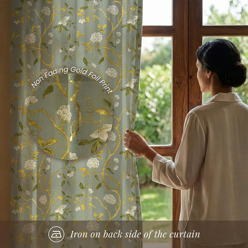 Close view of sage green floral foil curtain beside a wooden window
