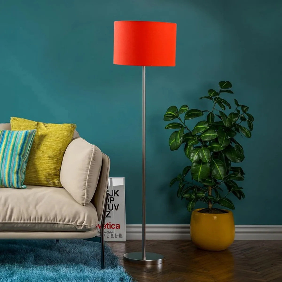 Orange drum shade floor lamp with steel base beside sofa and potted plant