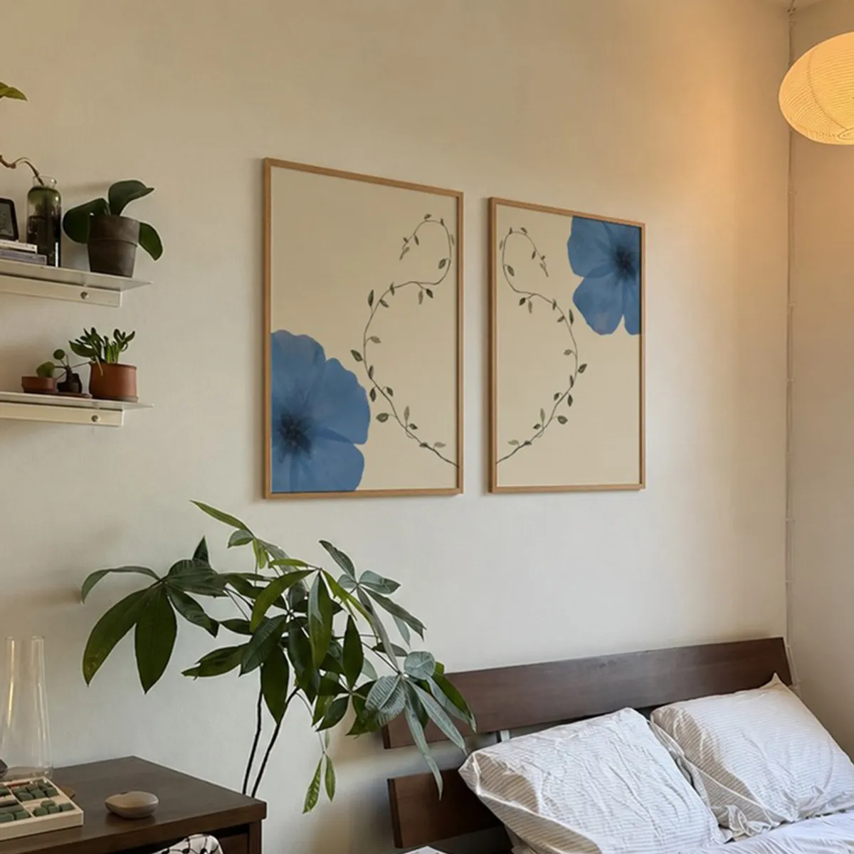 Pair of framed blue floral wall artworks displayed above a bedroom bed