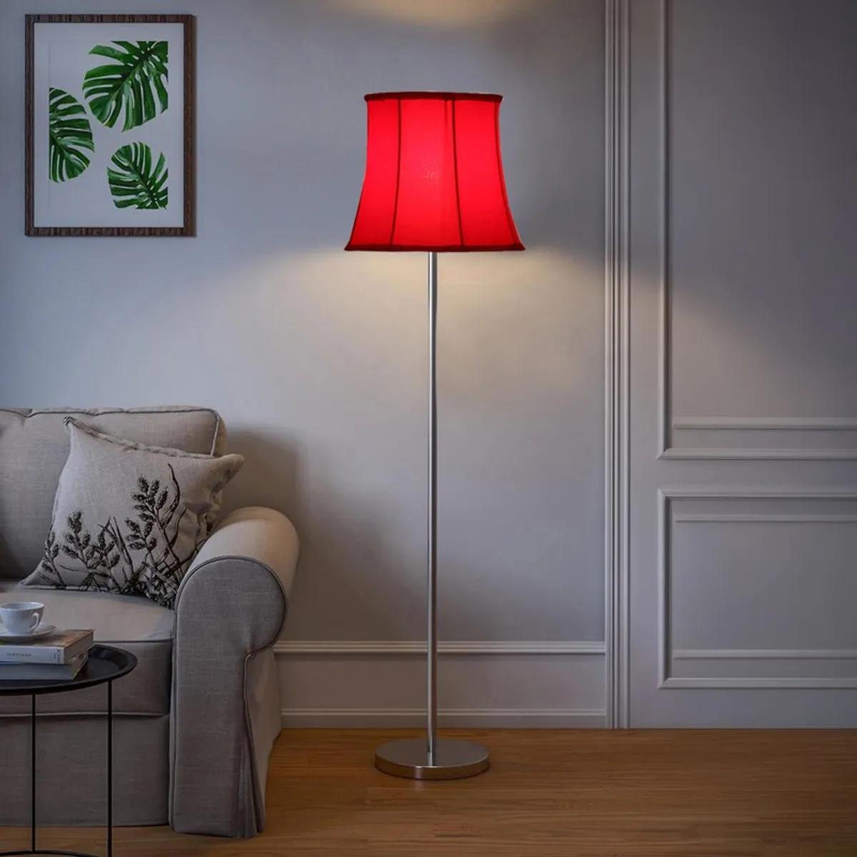 Red floor lamp with silver base beside a light grey sofa in a neutral room