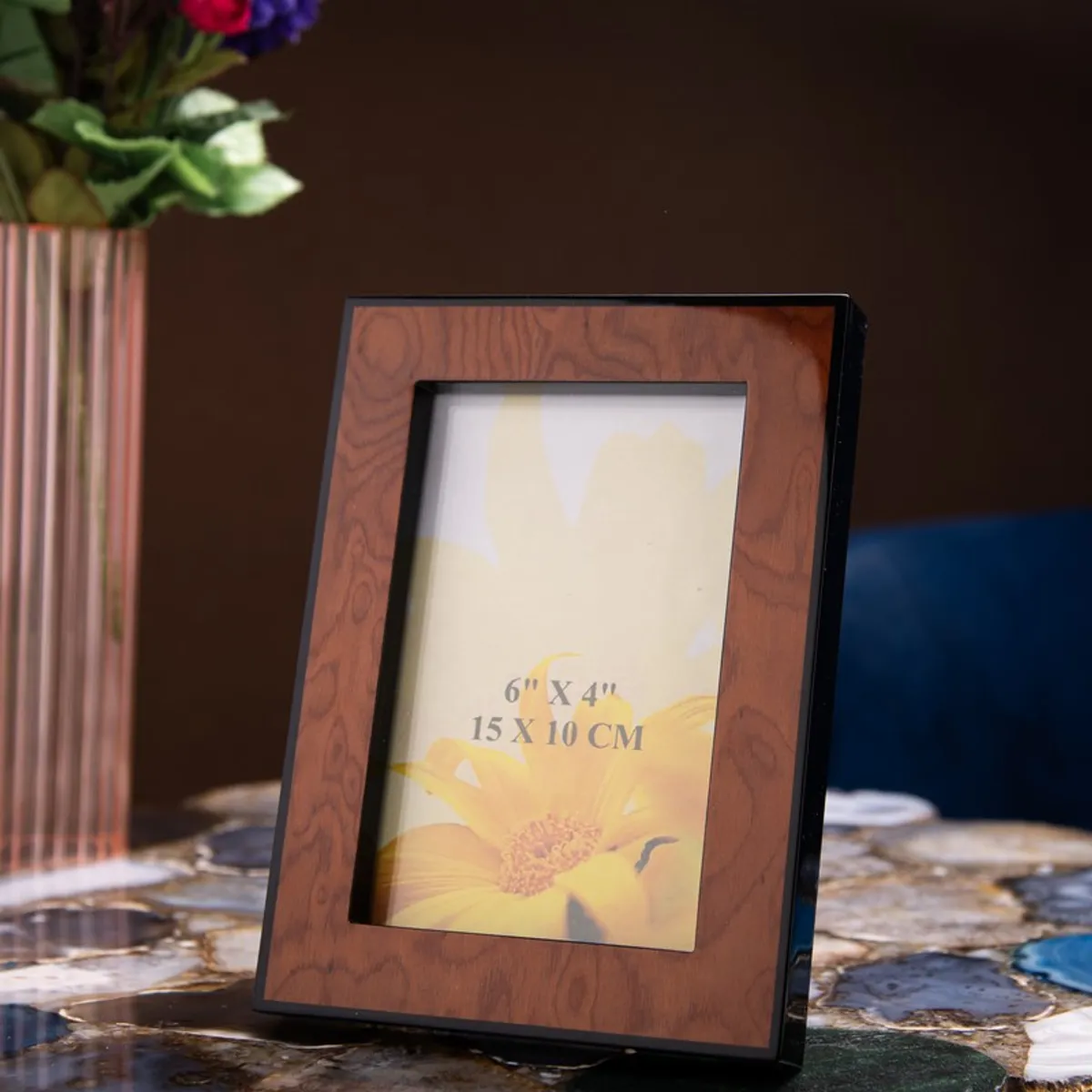 Brown rectangular photo frame styled on a table beside flowers