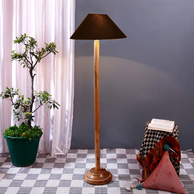 Wooden floor lamp with black shade in a styled room with a potted plant