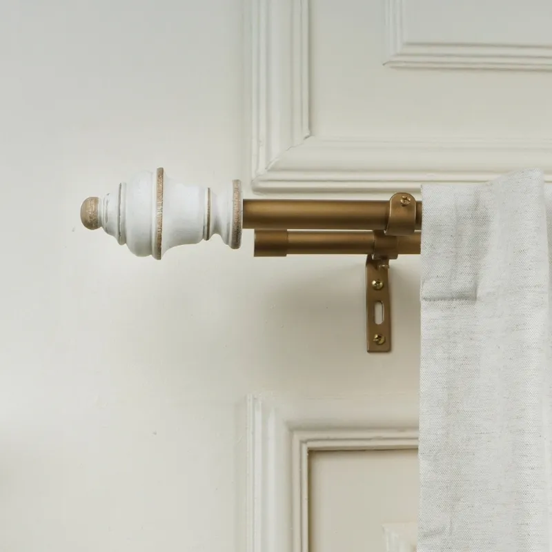 Double curtain rod with white finial and bracket mounted beside a white curtain