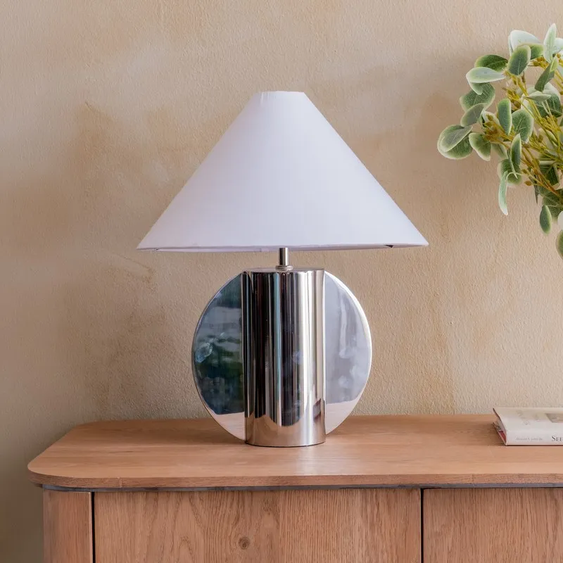 Chrome-finish table lamp with white shade styled on a wooden sideboard