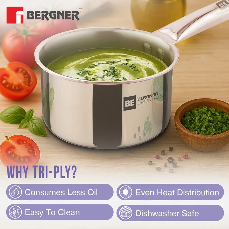 Glossy silver saucepan with green soup on a kitchen counter.