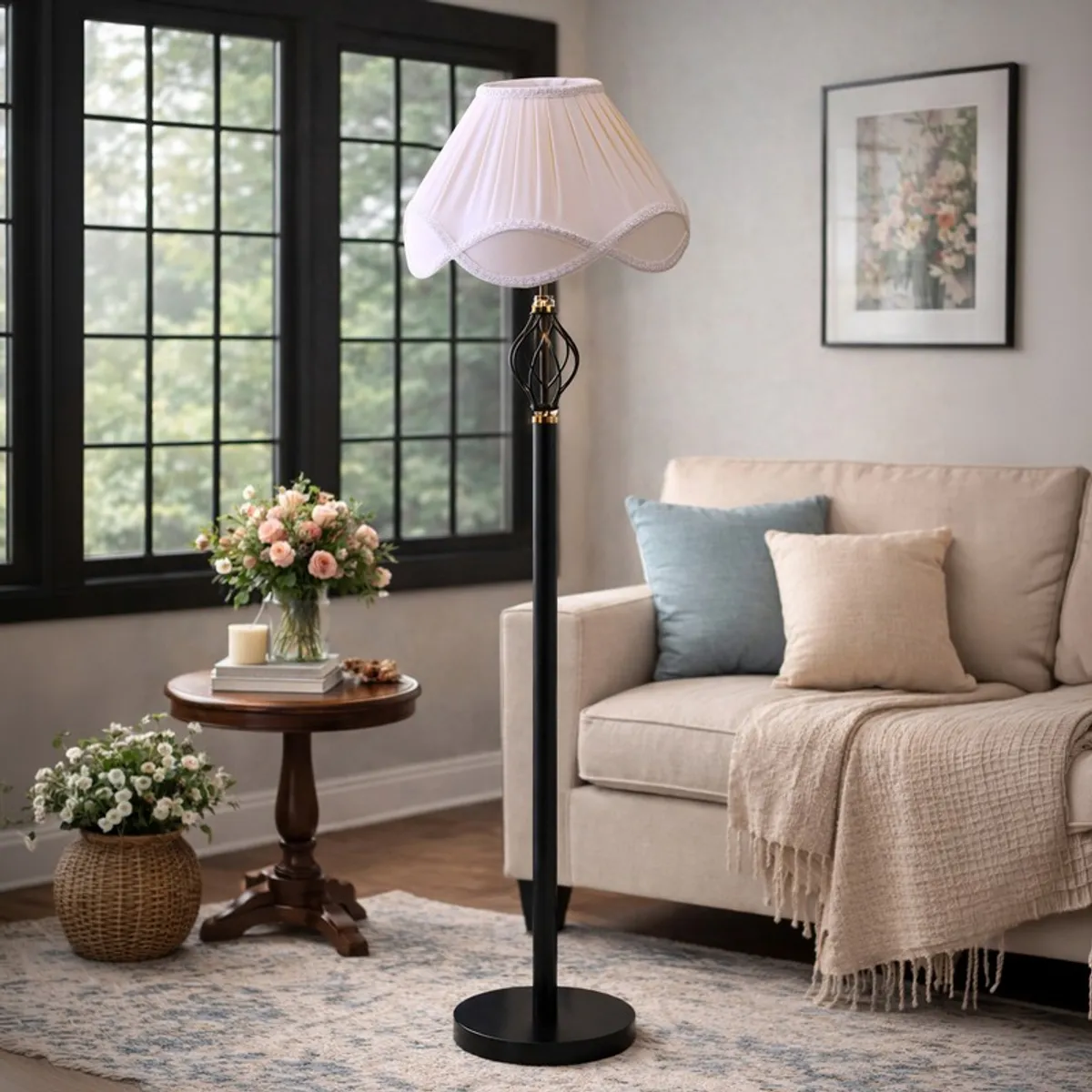 Black floor lamp with scalloped pale pink shade beside a sofa