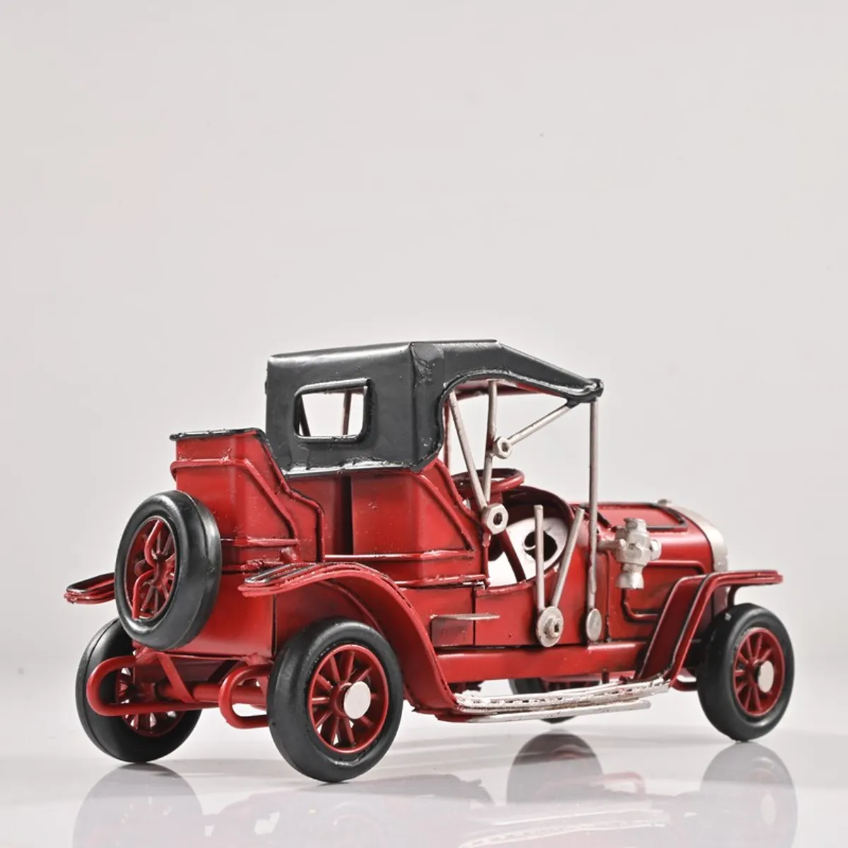 Rear side view of red vintage car showpiece on white background