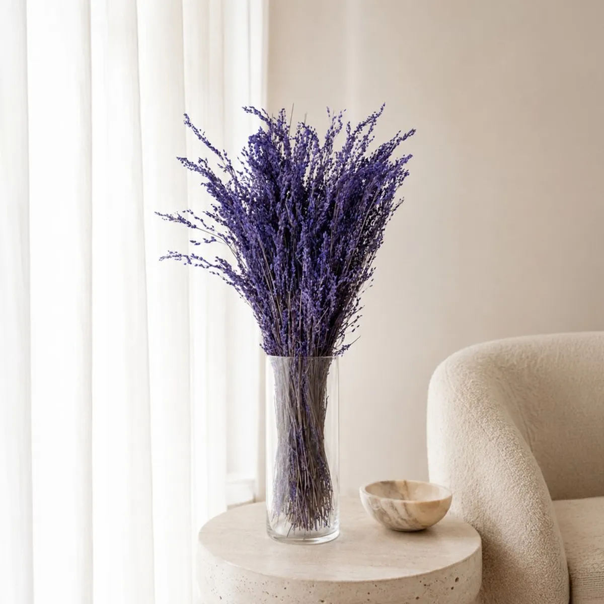 Purple dried flower bunch arranged in a clear vase on a round side table