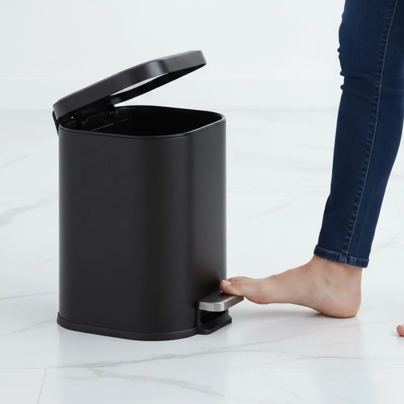 Black pedal dustbin with lid open beside a foot pressing the pedal