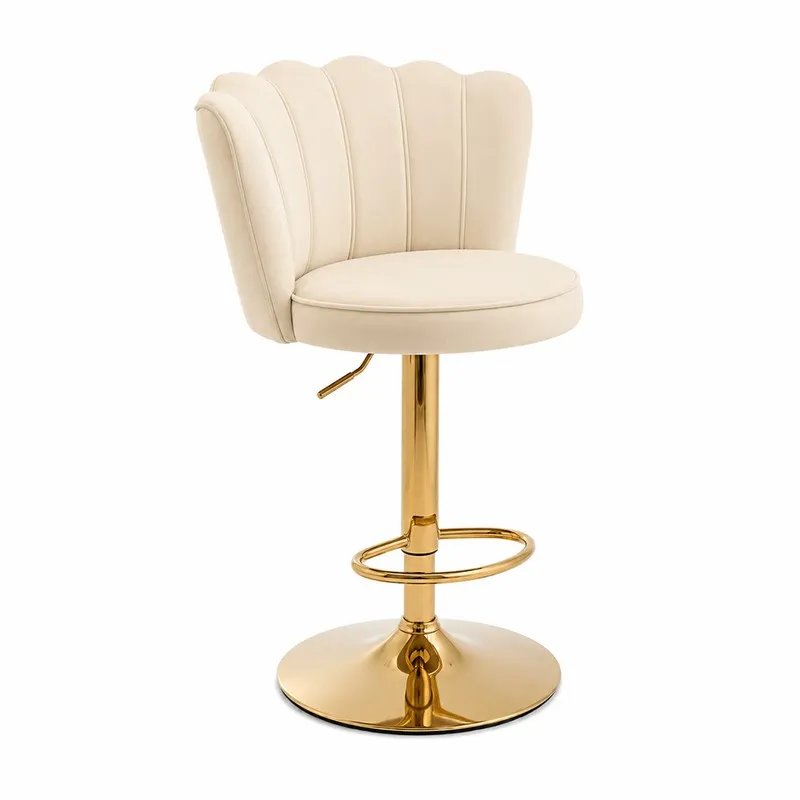 Angled view of a beige velvet bar chair with gold-tone pedestal base and footrest