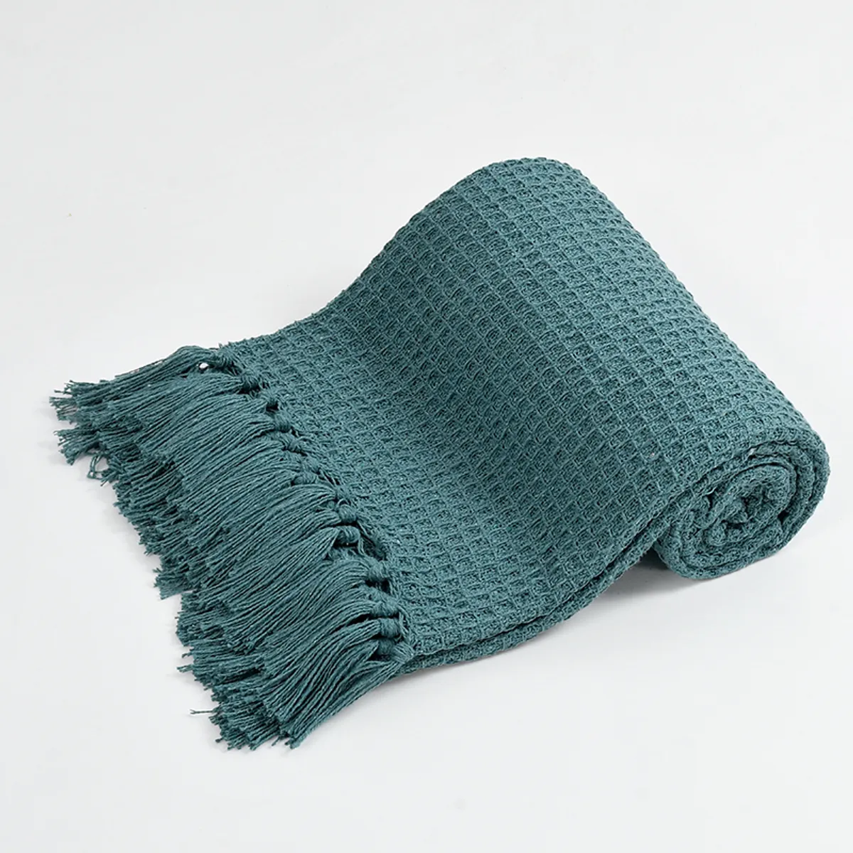 Rolled teal waffle throw showing waffle texture and fringe detail
