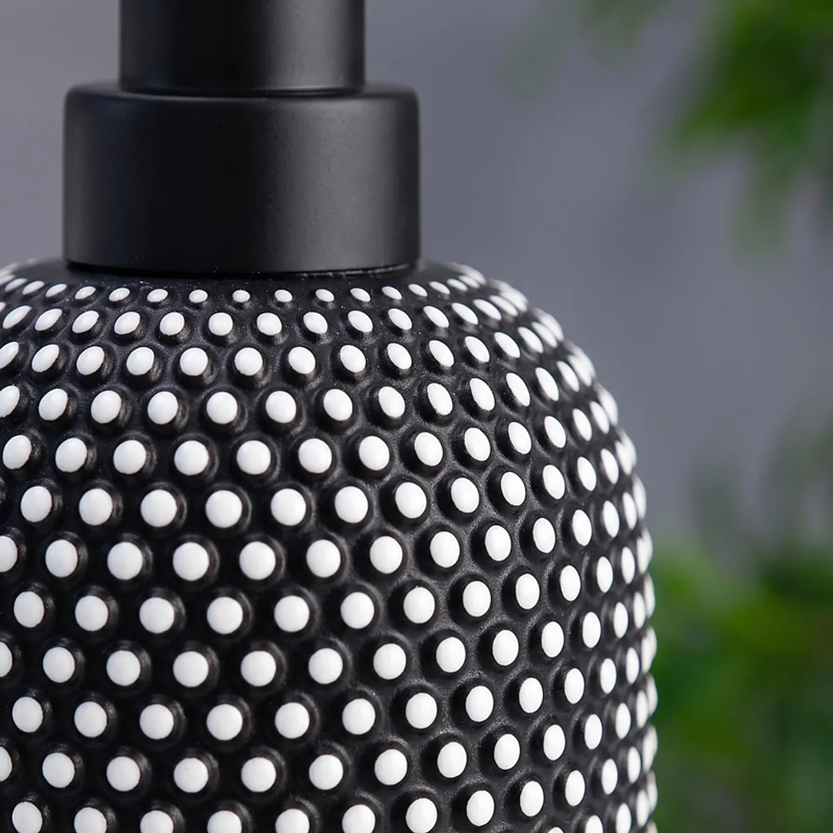Close-up of the black dotted textured surface of the soap dispenser