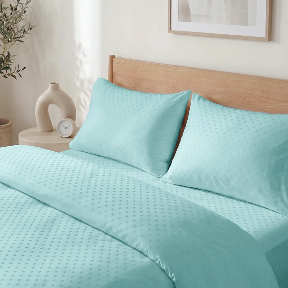 Close view of turquoise Swiss dot duvet cover styled with pillows