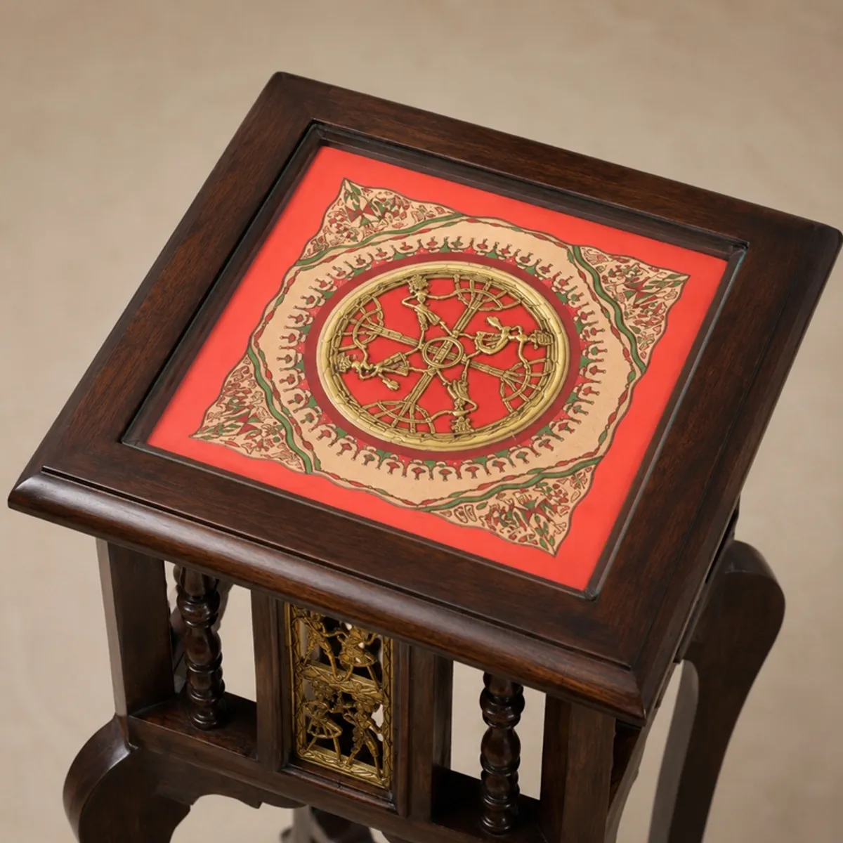 Close-up of the square tabletop with red, cream and green ornamental artwork.