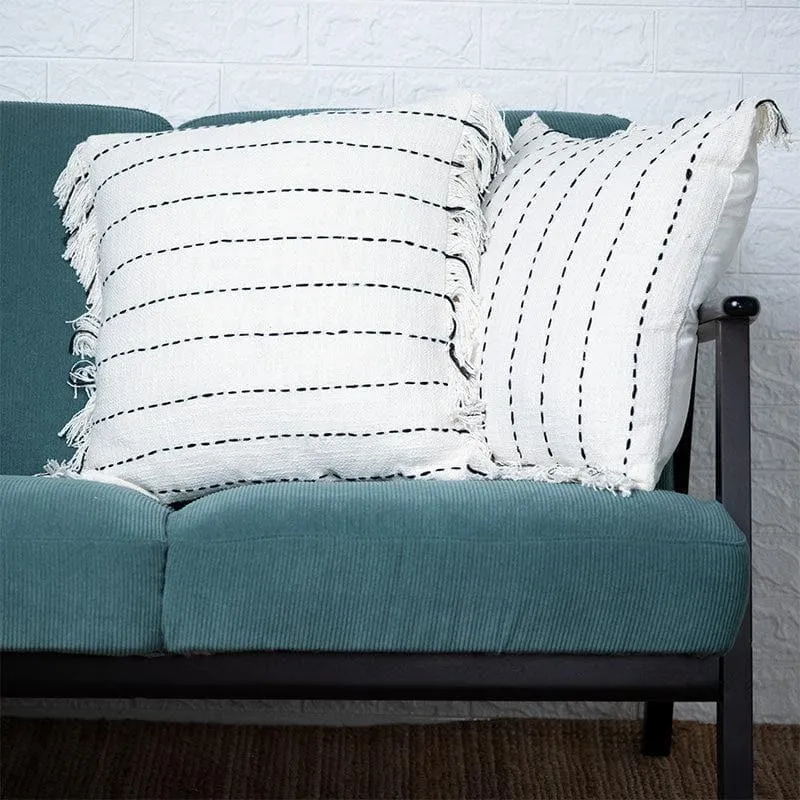 Two white striped cushion covers with fringed edges styled on a teal sofa