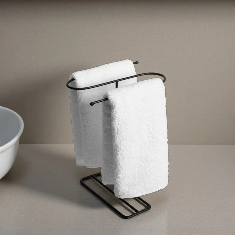 Black freestanding towel hanger holding white towels on a neutral counter
