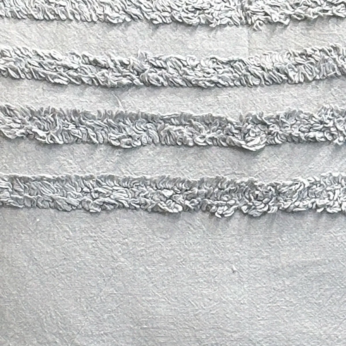 Detailed view of the cushion cover's soft grey fabric and raised stripe texture.