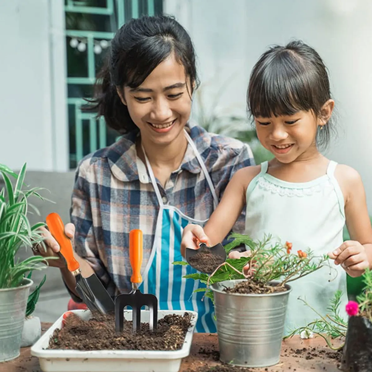 Adult and child gardening with small hand tools and potted plants