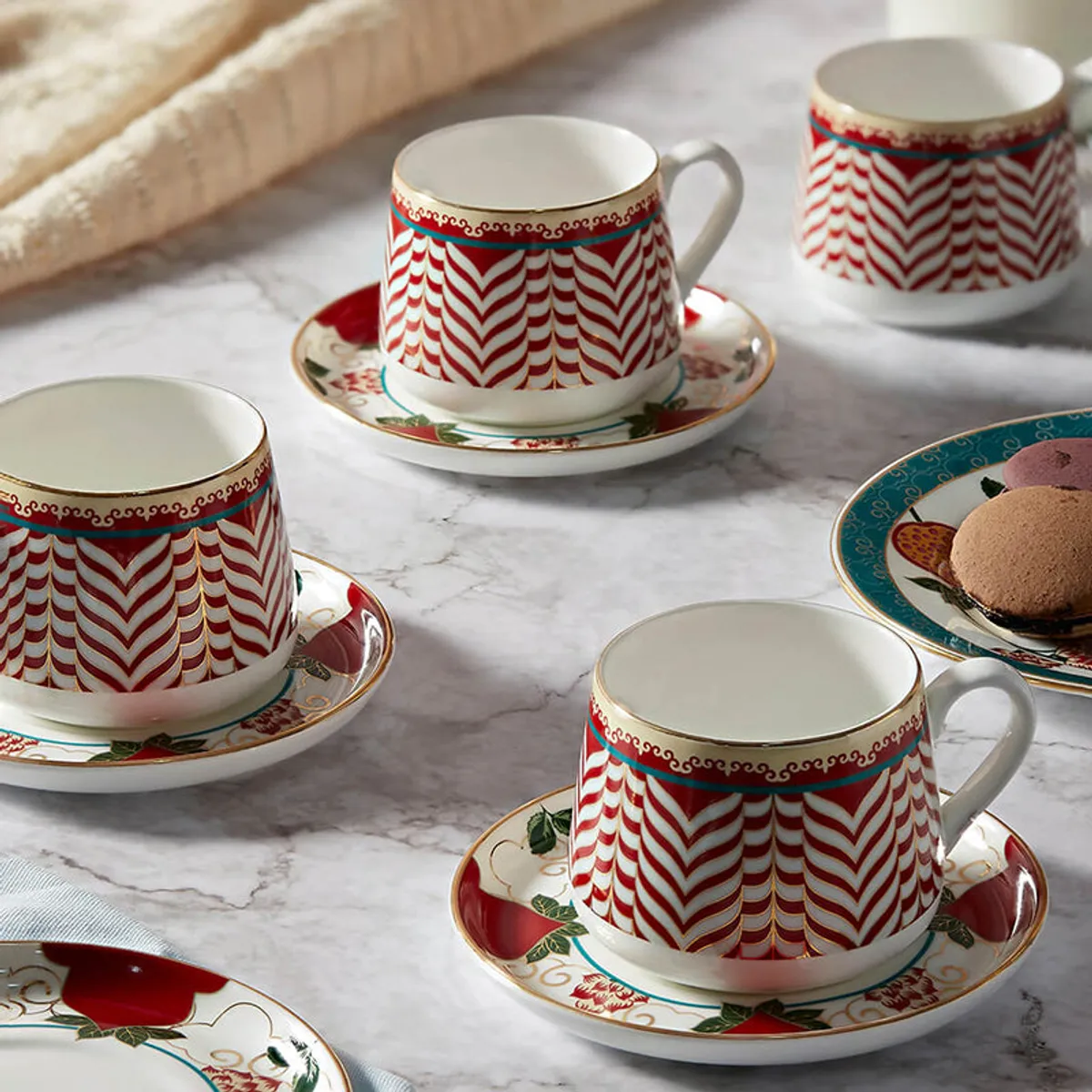 Red and white chevron cups with ornate saucers arranged on a marble table