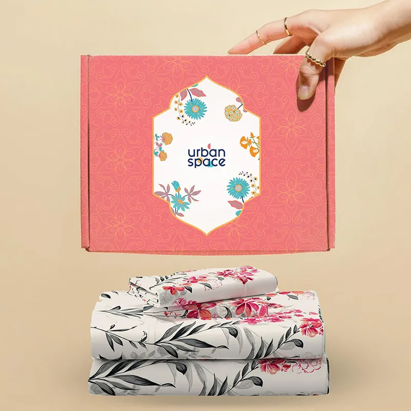 Folded floral bedsheet placed below a pink branded box