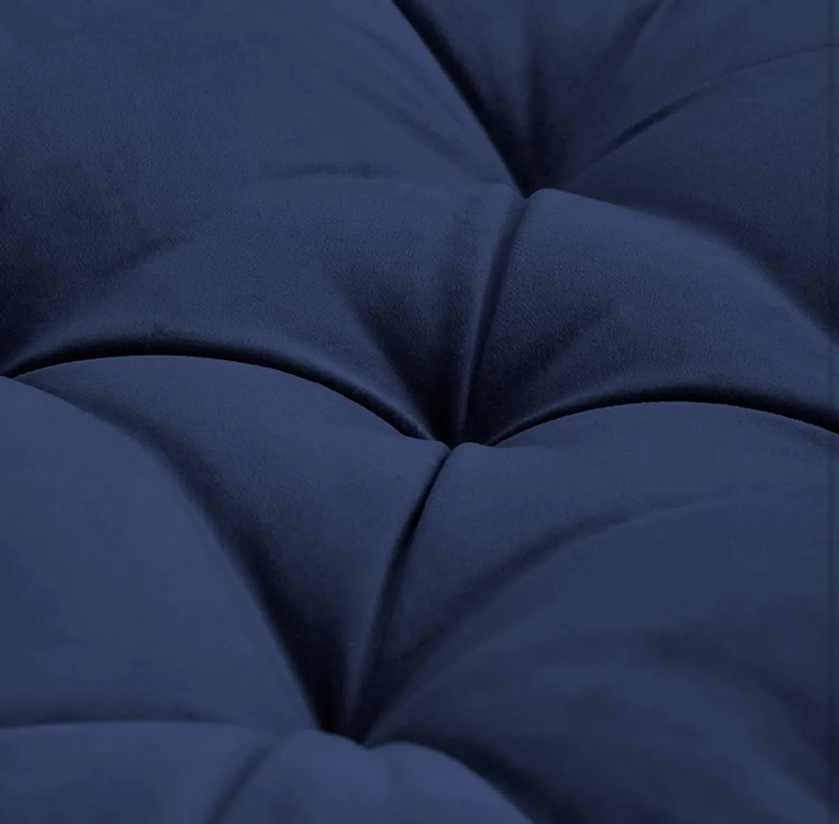 Detailed view of deep tufting on the navy blue velvet cushion