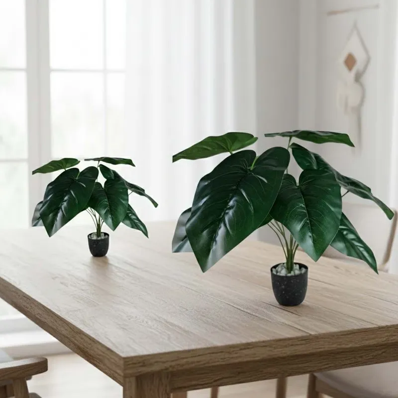 Two faux leafy plants in black pots arranged on a wooden table.